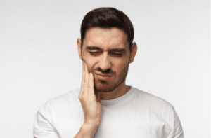 young man feeling pain holding his cheek with hand