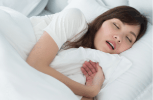 portrait of stressful exhausted woman snoring while sleeping on bed in bedroom environment