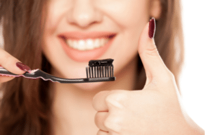 woman holding a black tooth paste with active charcoal