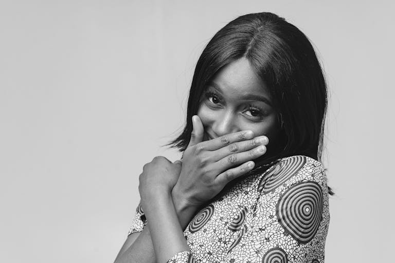 A woman covers her mouth playfully in a monochrome portrait, showcasing emotions.