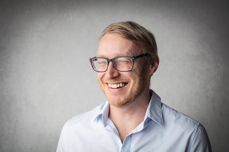 Studio portrait of a smiling man wearing eyeglasses, exuding joy and happiness.